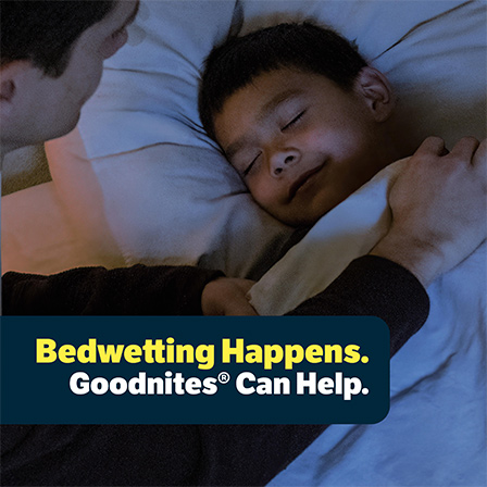 Parent tucking in a sleeping child at bedtime with title card saying: “Bedwetting Happens. Goodnites® can help.